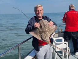 An Angler holding a Thornback Ray